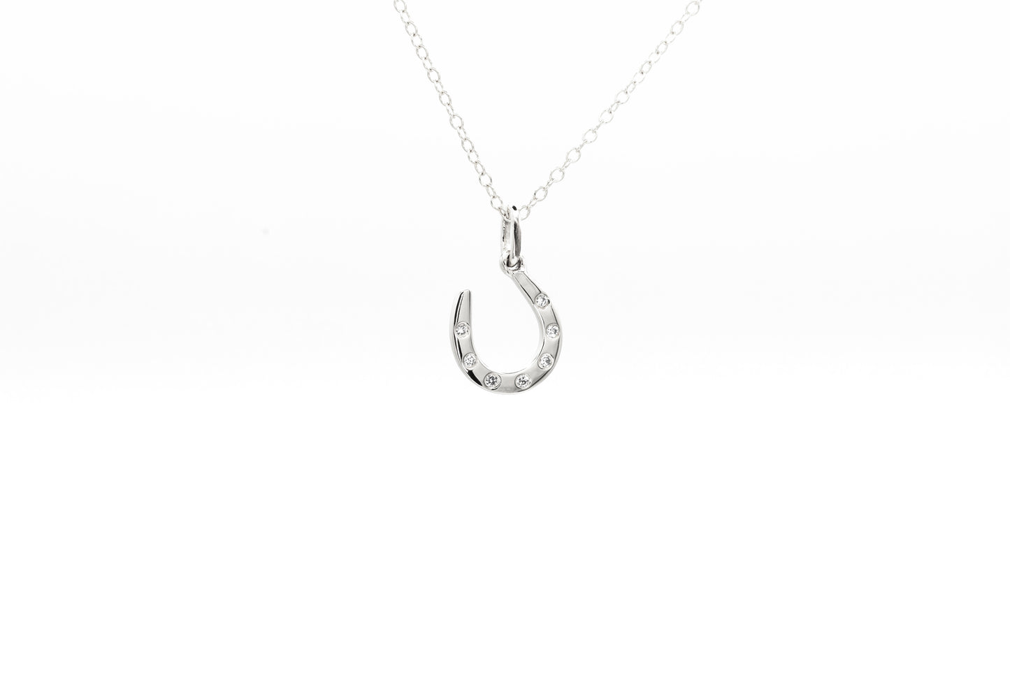 White gold horseshoe pendant necklace on a white background