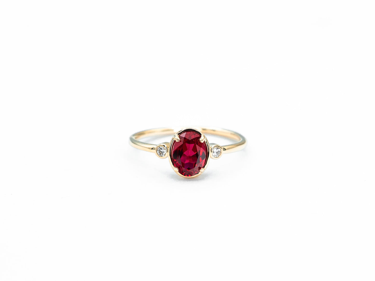 Oval ruby and diamond bezel set ring in yellow gold, front view