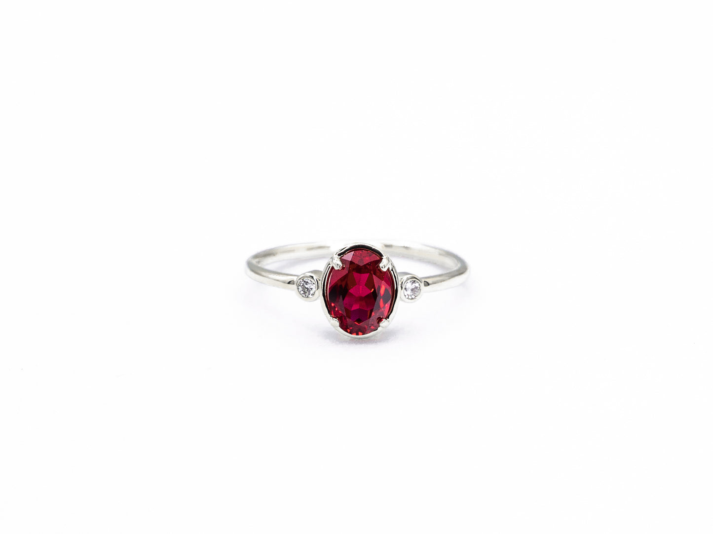 Oval ruby and diamond bezel set ring in white gold, front view