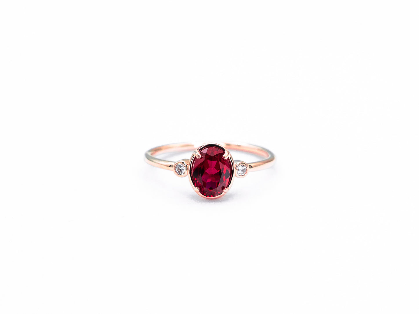 Oval ruby and diamond bezel set ring in rose gold, front view
