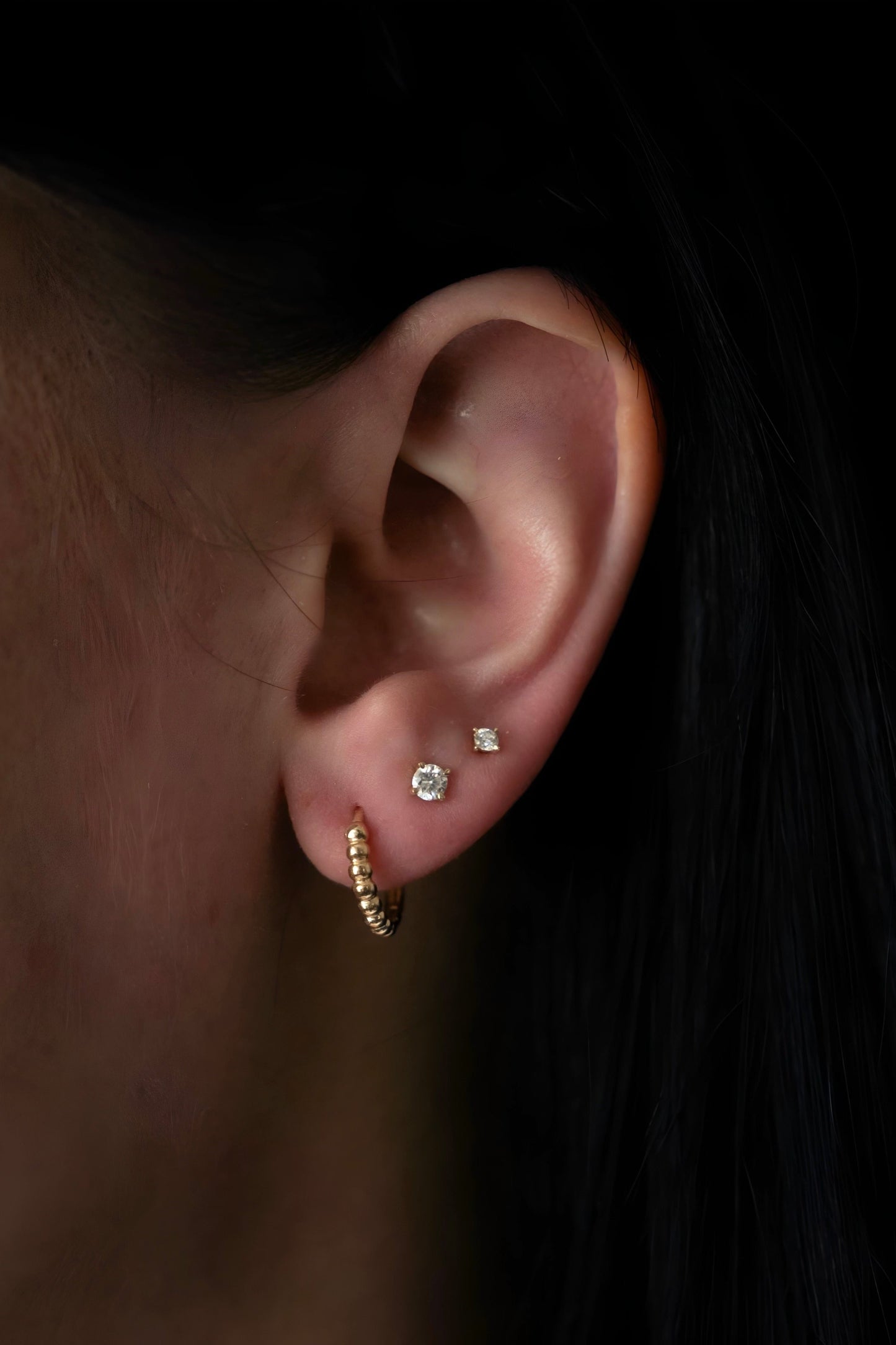 yellow gold, beaded hoop earrings being worn on ear, side view