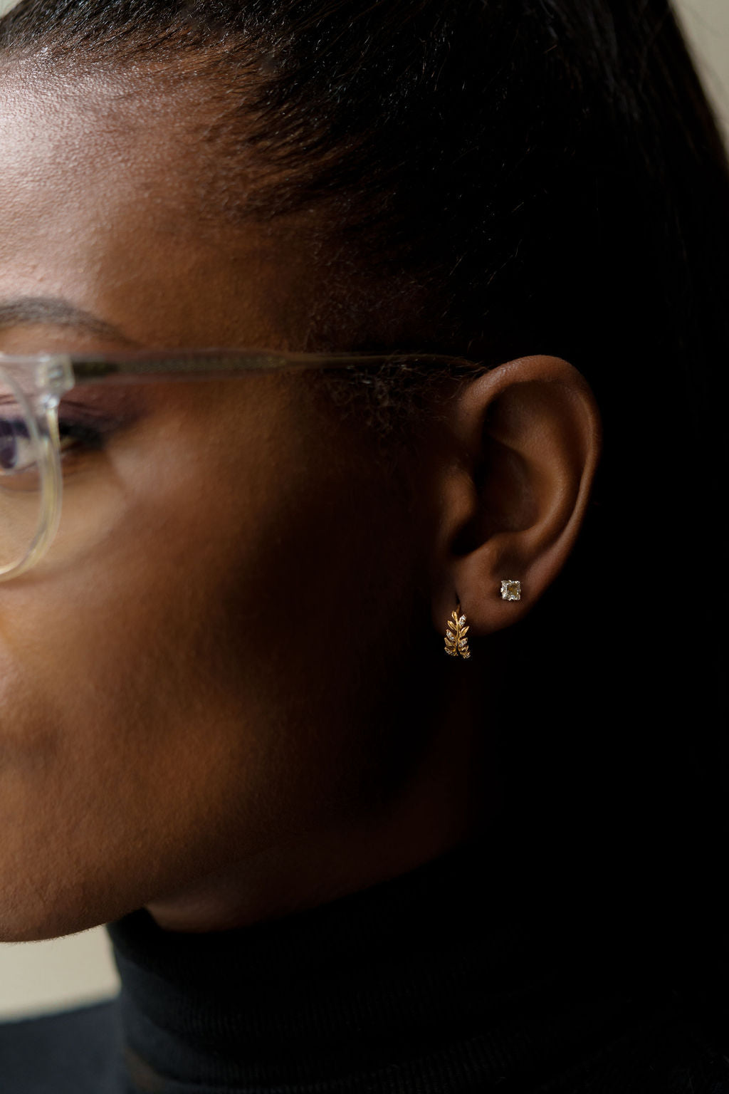 Yellow gold, leaf shaped diamond hoop earrings being worn on ear, side view