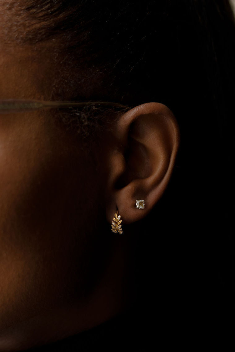 Yellow gold, leaf shaped diamond hoop earrings being worn on ear, side view