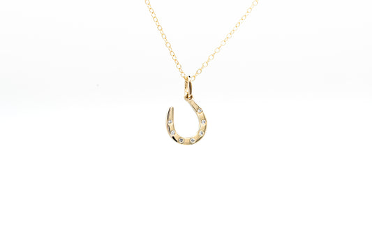 Gold necklace with a horseshoe pendant on a white background