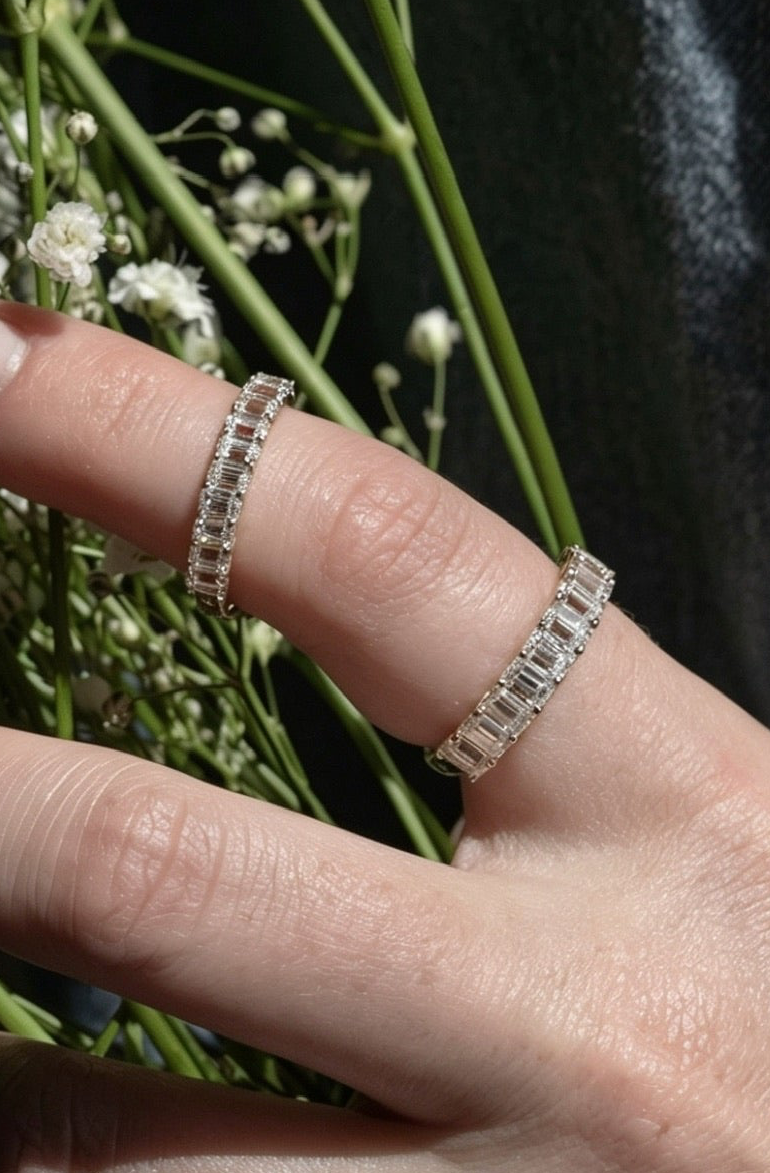 Hand holding a small bouquet of flowers with a ring on a dark background