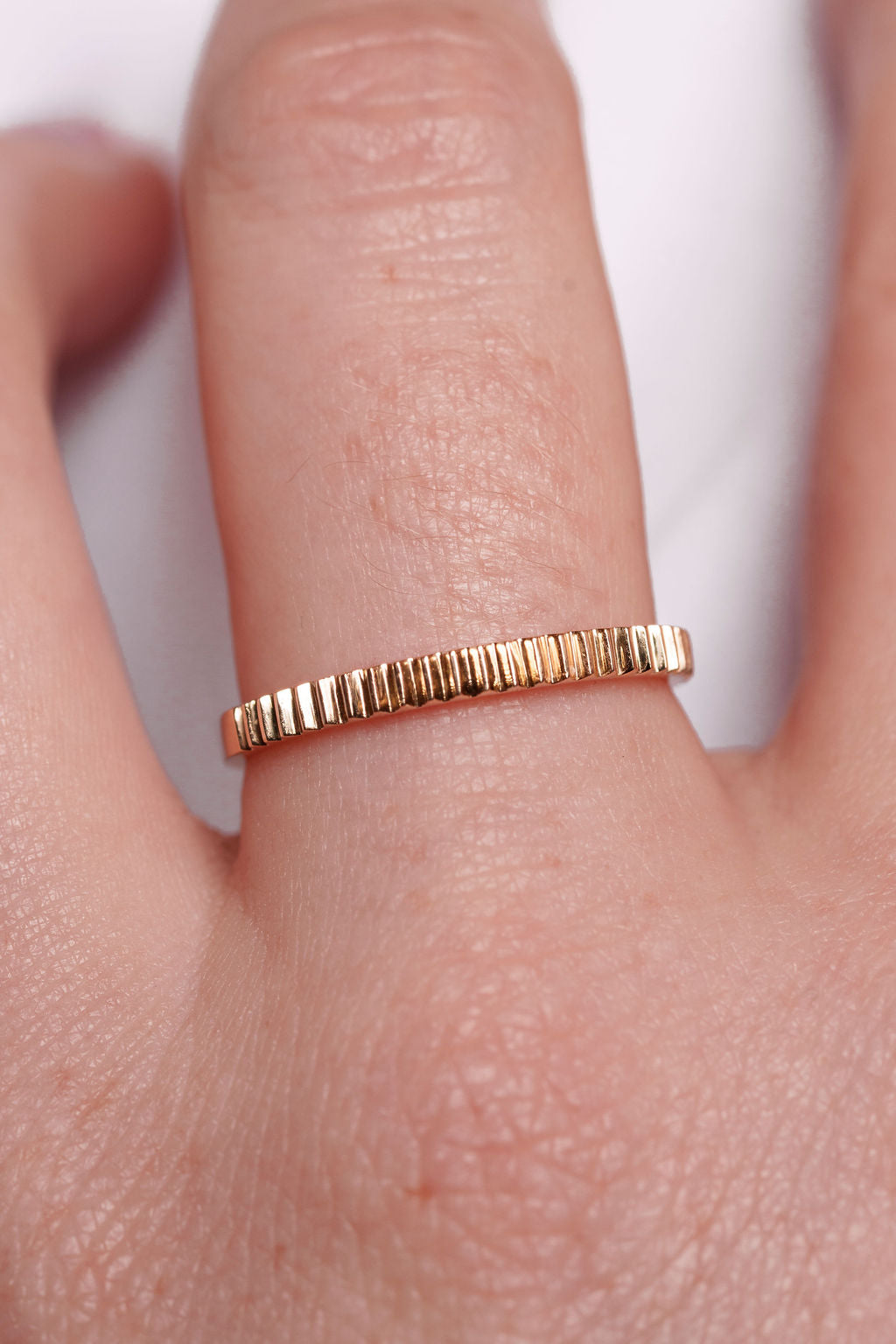 yellow gold ring on a finger with a white background