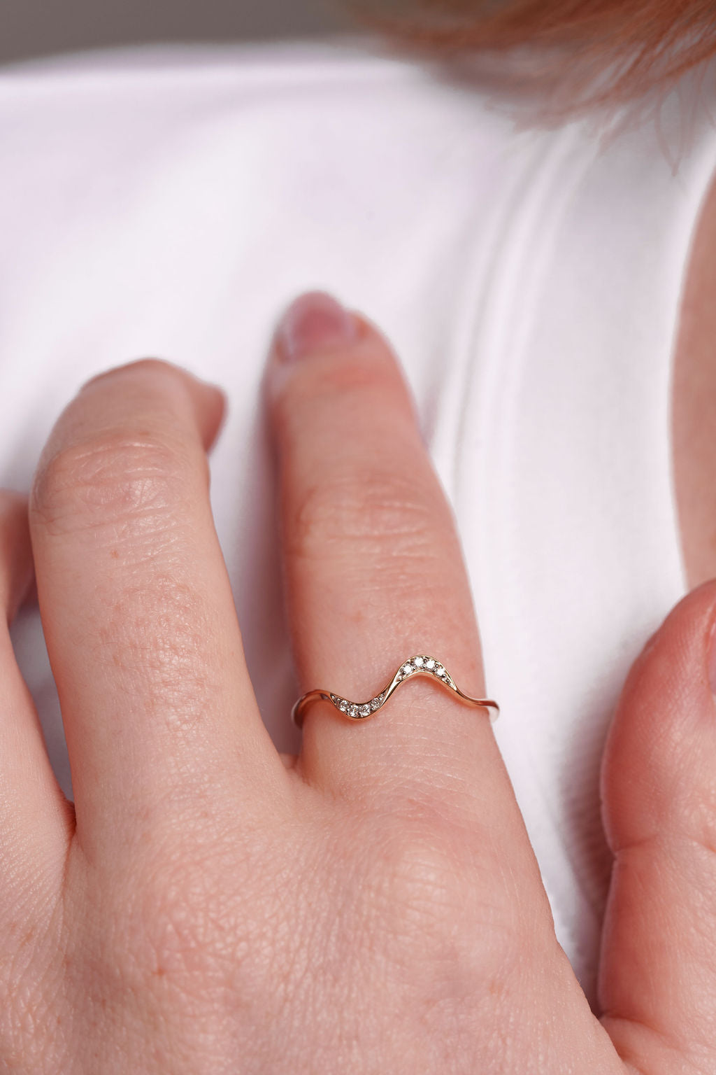 yellow gold ring on a person's finger against a white background